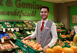 Mitarbeiter steht in der Obst- und Gemüseabteilung