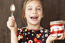 Kind mit Erbeerpüree und Joghurt