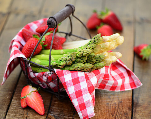 Grüner und weißer Spargel sowie leckere Erdbeeren in einem Korb